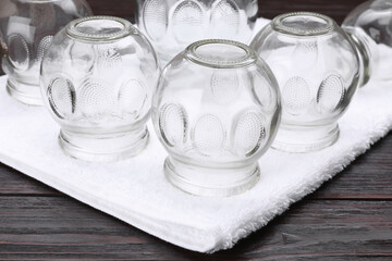 Glass cups and towel on wooden table, closeup. Cupping therapy