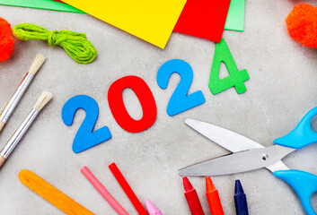 2024 written in colorful numbers with colorful craft supplies on mottled grey