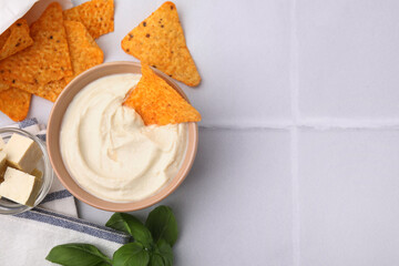 Delicious tofu sauce served with nachos chips on white tiled table, flat lay. Space for text
