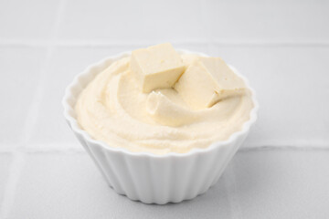 Delicious tofu sauce in bowl on white tiled table, closeup