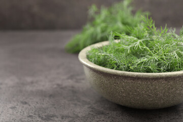 Bowl of fresh dill on grey table, closeup. Space for text