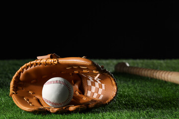 Baseball glove and ball on artificial grass against black background. Space for text