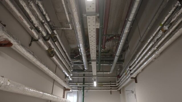 Pipes, ventilation and air conditioning in an underground garage. New house. Pipes in the basement of a new house. New metal pipes in the basement of a residential building.