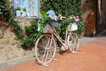 Rower w kwiatach na tle zielonych liści  - obrazy, fototapety, plakaty