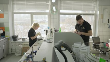 Dental technicians working in the modern clinic laboratory. Dental clinic technicians manufacturing the artificial teeth replacements. Dental clinic technicians using small tools on the fake crowns.