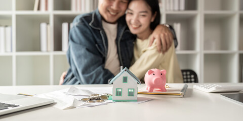 Happy asian family young couple love hand . piggy bank to save and model home for saving money to...