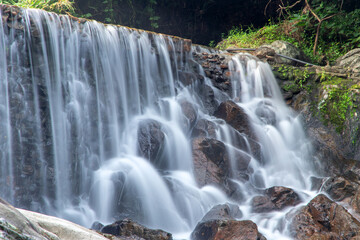 Small waterfall with water splashing and tumbling over the rocks in the forest on a bright sunny,kra-ang waterfall