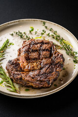 Asian cuisine. large grilled pork steak with rosemary and thyme. on a white plate, on a black background