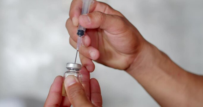 Check the dose in the syringe and remove the air from the syringe.Syringe with liquid being drawn into syringe.Testosterone.