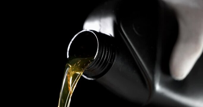 worker pouring car engine oil from bottle on black background. motor maintenance