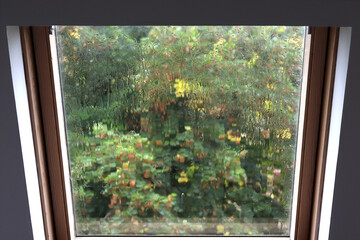 la pluie sur la vitre d'une fenêtre de toit donne un aspect abstrait au paysage