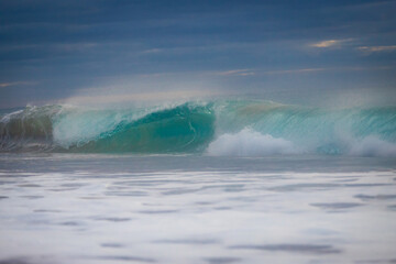 Blue wave breaking on the beach.