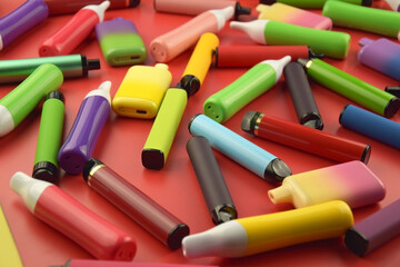 Set of multicolor disposable electronic cigarettes on a red background.