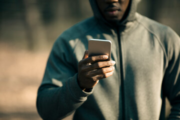 Young man using a smartphone while exercising in a outdoor park