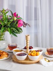 Fresh and bright continental breakfast table with jam, cheese, nuts and croissant. Vertical