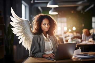 poc woman with angel wings wearing suit working at laptop desk in office