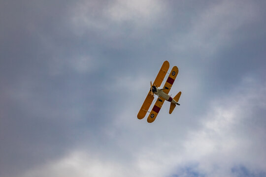 Leszno, Poland - June 16 2023: Antidotum Airshow Leszno 2023 and acrobatic shows of yellow Boeing Stearman plane on a blue cloudy sky