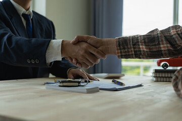 Car salesman makes a deal with his customer in car business showroom, car sales, agreement, gesture and handshake concept at car show