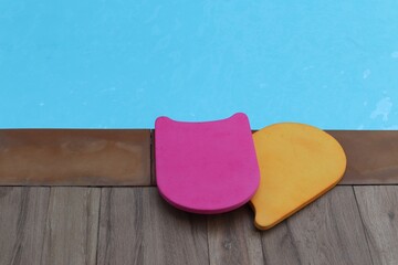 Pink and yellow float foam board at the edge of the pool