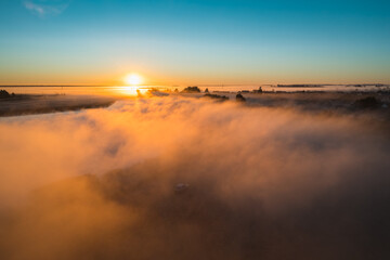 Fog reflects sunlight on autumn morning at dawn
