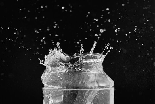 Top of transparent glass and water splash isolated on black background.