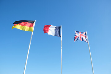 Flags of Germany, France, and Great Britain waving . Clear blue sky in the background 