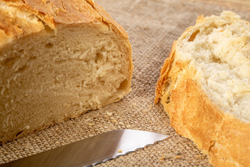 A cut loaf of white Ukrainian bread and a kitchen knife on a burlap napkin