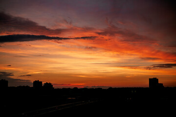 Cloudy red-blue sunset over dark silhouettes of city buildings, top view. Evening view.