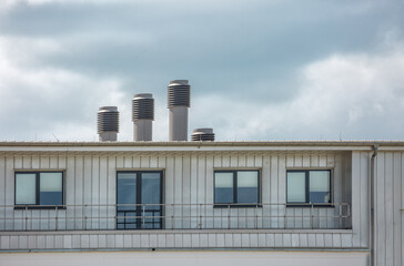 Drei unterschiedlich große , moderne Abluftrohre auf einem Hausdach weißer Holzfassade