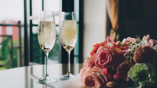 Wedding rings fall into glasses of champagne, slow motion. Wedding bouquet, wedding background.