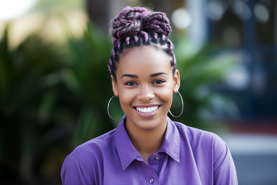 portrait of young poc woman with dyed purple braids in hair and shirt outside