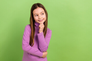 Portrait of minded schoolgirl with long hairstyle dressed violet pullover thoughtfully look empty...