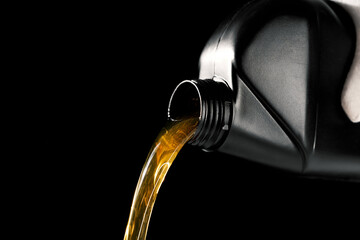 pouring new motor oil from bottle into car engine. isolated on black background - obrazy, fototapety, plakaty