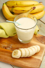 Vaso de leche natural y fresca junto a unos plátanos sobre un fondo de madera. Vista superior y de...