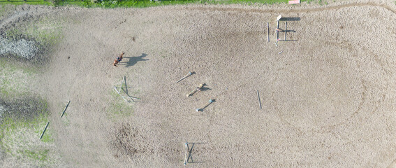Aerial view of three horsemen. A riding field with fence and obstacles to train horses. In this...