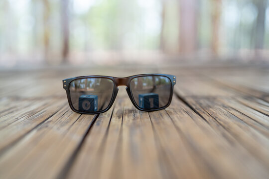 Sunglasses are placed on a wooden background and there are shadows of the numbers zero and one.