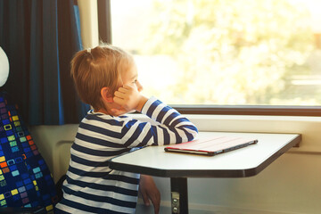 Cute child looking out the train window. Little boy is traveling on the train. Kid travels on a train.