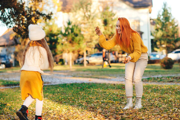 Mother and child girl throwing leaves in autumn park. Autumn holidays, lifestyle, childhood.