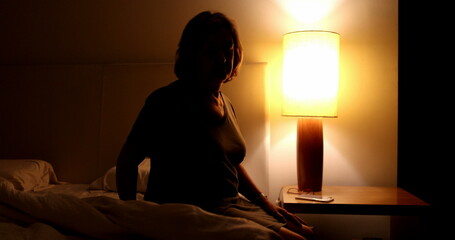 Woman sitting on the side of th ebed preparing to go to sleep