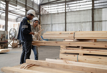 Diverse ethnic workers standing in warehouse examining hardwood material for wood furniture production. Engineer team wear safety hardhat working in lumber pallet factory. Diversity people check stock