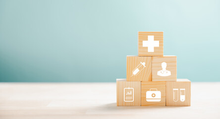 Healthcare and insurance visualized by a pyramid arrangement of wooden cubes. Crowning medical icons symbolize safety. Blue background offers copyspace to articulate Health Insurance concepts.