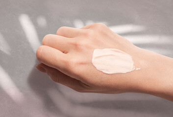 Cosmetic bb or cc cream smudge on woman hand swatch on beige background
