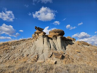 Outdoor nature landscape of dry and arid prehistoric hoodoo formations with brown grass and blue...