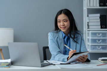 Asian businesswoman uses laptop computer with documents The notebook is on the table. Planning to analyze the report Financial statistics Investments, business plans, ideas, startup businesses.