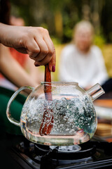 A tea master stirs boiling water in a transparent teapot