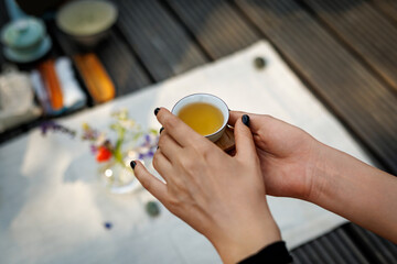 Tiny Chinese teacup in woman's hands during a tea ceremony.