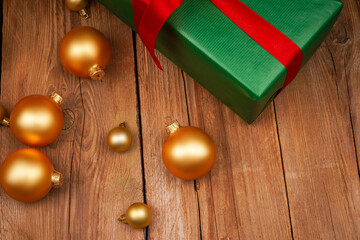 Festive gift box and golden Christmas tree decorations on wooden background. Holiday concept. Christmas, New Year, birthday, women's holiday.