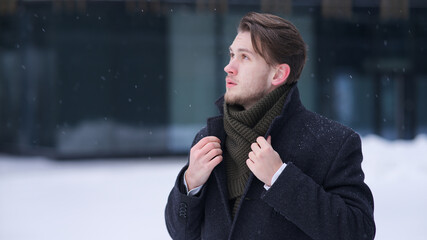 Portrait of young handsome businessman or student outdoors at winter cold snowy day
