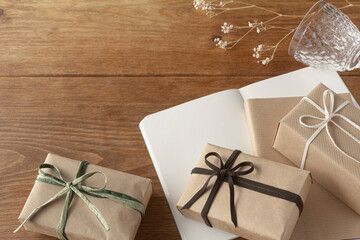 Multiple gifts in natural taste are arranged on a wooden table with notebooks, books and glasses