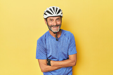 Cyclist wearing helmet in yellow studio laughing and having fun.